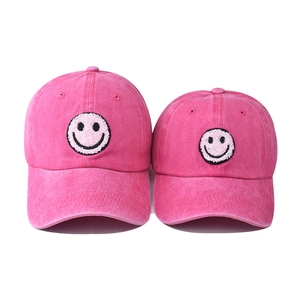 Detail of pink washed cotton baseball caps with chenille smiley face embroidery patches