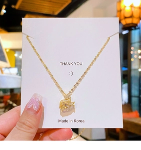 Detailed view of a gold swan necklace with sparkling zircon crystals on a gift card
