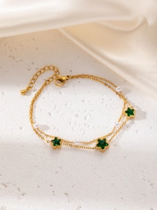 Detail of gold double-layer bracelet with green star stones and small white pearls