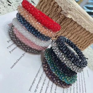 Colorful crystal bead hair ties in multiple shades stacked elegantly on a neutral surface