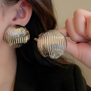 Close-up of silver striped ball earrings with textured metallic finish on model