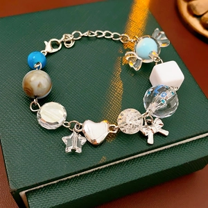 Detail of beaded bracelet with candy, star, and heart charms on green jewelry box