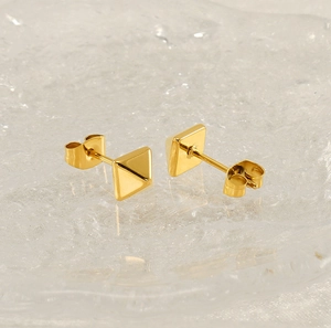 Détail de boucles d'oreilles pyramides dorées sur verre avec fermoirs papillon classiques