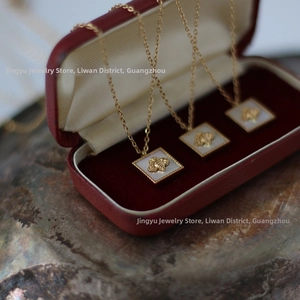Macro view of gold-plated square shell pendants with 3D bee motifs in a velvet box