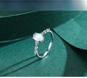 Macro shot of S925 silver moonstone ring with side zircons on a dark green background