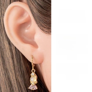 Close-up of gold-plated fishtail earrings with pink zircon stones and moonstone drop