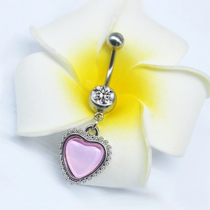 Detailed view of silver navel ring with pink heart pendant beside a frangipani flower