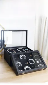 Joyero negro con tapa de vidrio que muestra la organización de collares y anillos