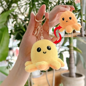 Detail of reversible octopus plush keychain showing yellow smile and orange sad expressions