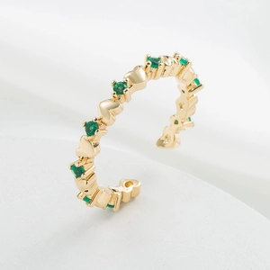 Macro detail of 18K gold plated heart ring featuring sparkling green zircon gemstones