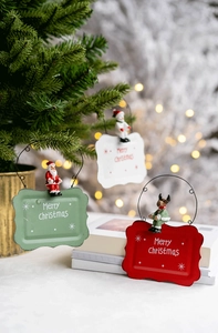Close-up of Merry Christmas metal signs featuring festive Santa, snowman and elk characters