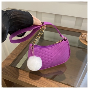 Détail du sac violet en daim avec matelassage en V et breloque pompon blanc soyeux
