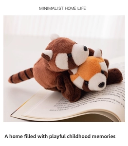 Close-up of cute plush red panda dolls with striped tails on an open book