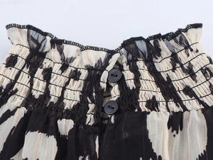 Detail view of smocked waist with black buttons on a monochrome chiffon ethnic long dress