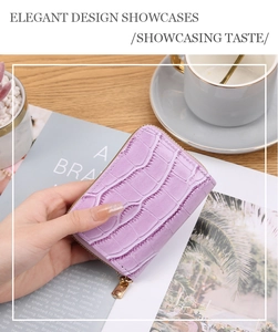 Elegant purple crocodile pattern card holder with gold zipper held in a lifestyle setting