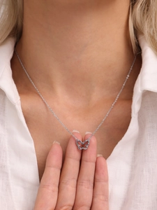 Close-up of a silver butterfly necklace with colorful crystals on a white shirt model
