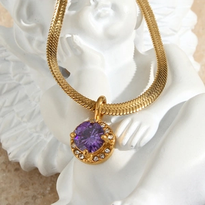 Luxury gold snake chain necklace with a round purple zircon pendant on a white sculpture