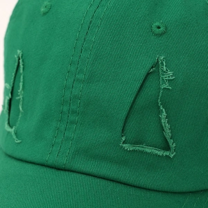 Close-up of green cotton baseball cap featuring unique triangle distressed cutout details