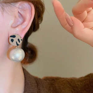 Gros plan de boucles d'oreilles rondes à imprimé léopard avec perle blanche sur mannequin