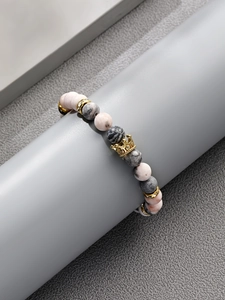 Detailansicht des Steinperlenarmbands in Rosa und Grau mit goldener Krone und Anhänger