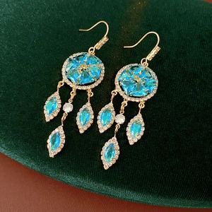Close-up of vintage gold tassel earrings with blue stones and crystals on velvet