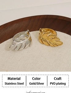 Detailed view of gold and silver leaf-shaped rings on a textured wooden and fabric base