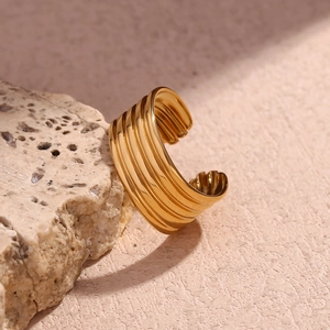 Bague ouverte multicouche plaquée or 18 carats sur pierre volcanique sous lumière chaude