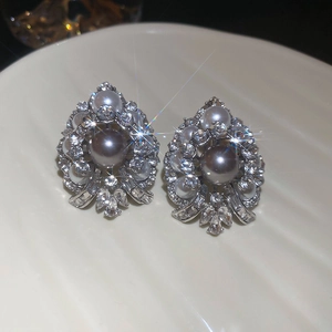 Close-up of vintage drop pearl earrings with sparkling rhinestones on a white plate