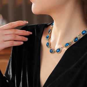 Gros plan d'un collier vintage doré avec pierres bleues porté par un mannequin