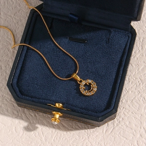 Close-up of a 18K gold-plated smiley face pendant with zircons in a navy blue velvet box