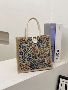 Floral linen tote bag with braided handles and wooden button on a minimalist background