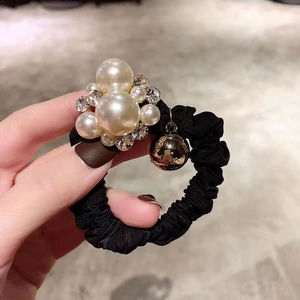 Close-up of black scrunchie featuring elegant white pearls and sparkling rhinestones