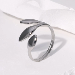 Close-up of polished silver leaf stainless steel ring on white textured stone background