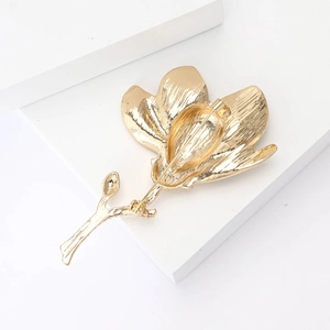 Close-up of golden enamel magnolia brooch showing intricate petal texture and metallic luster