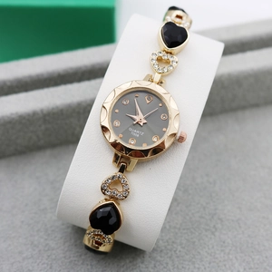 Detailed macro of gold heart charm bracelet watch with crystal accents and grey dial