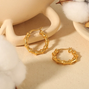 Bamboo textured 18K gold-plated C-shaped stainless steel hoop earrings in a warm setup