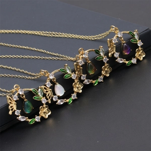 Détails de quatre colliers dorés avec pendentifs fleurs et papillons et gouttes de cristal