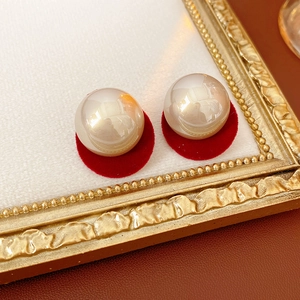 Detailed view of cream pearls with red velvet circular backings in a gold frame