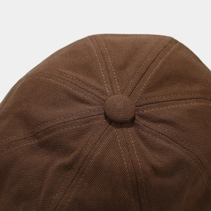Close-up of dark brown newsboy cap crown with reinforced stitching and top button