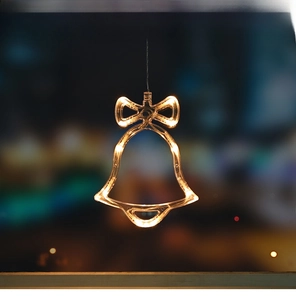 Detail of warm white LED Christmas bell light with bow decoration for festive window display