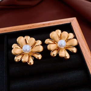 Detailed view of 18k gold plated flower earrings with a central pearl on black velvet