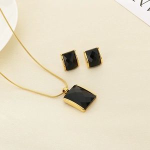 Detailed set of gold necklace and stud earrings with faceted black rectangular stones