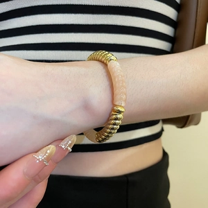 Detail of pink resin and gold metal beads with spiral texture on beaded bracelet