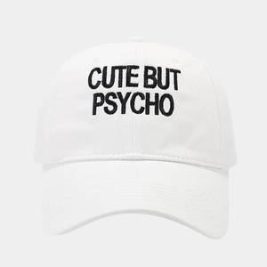 Detail of black 'CUTE BUT PSYCHO' embroidery on a white cotton baseball cap