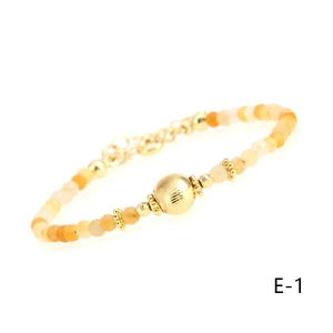 Detailed close-up of carnelian beaded bracelet with textured gold cylinder charm