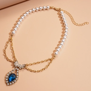 Detail of vintage necklace with imitation pearls, blue teardrop gem and rhinestone bow