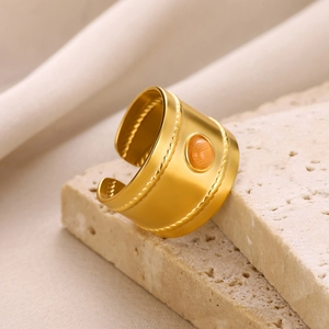 Detailed view of gold stainless steel ring with orange gemstone and braided texture