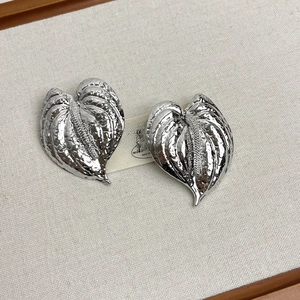 Détail des boucles d'oreilles feuille d'anthurium argentée avec texture martelée