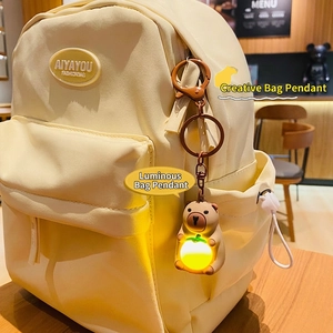 Luminous Capybara keychain plush charm with warm light attached to a beige backpack