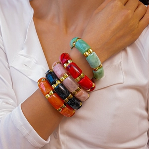 Detail of colorful resin acrylic bracelets with geometric marble patterns and gold beads
